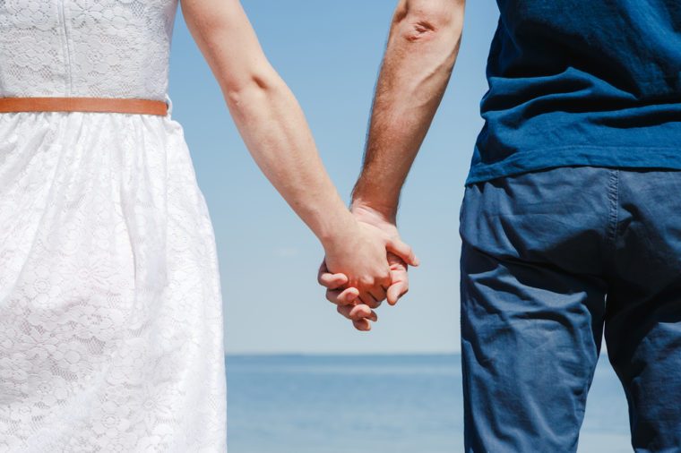 Close up of loving couple holding hands on a beach near the sea