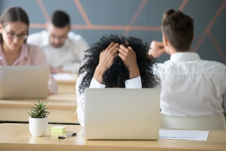 Frustrated african woman feeling despair panic shock sitting in shared office with laptop holding head in hands, upset stressed black employee or student tired of work, worried about online problem