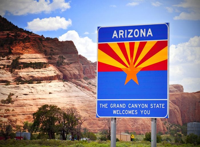 Arizona welcome sign at the state border with red rocks background