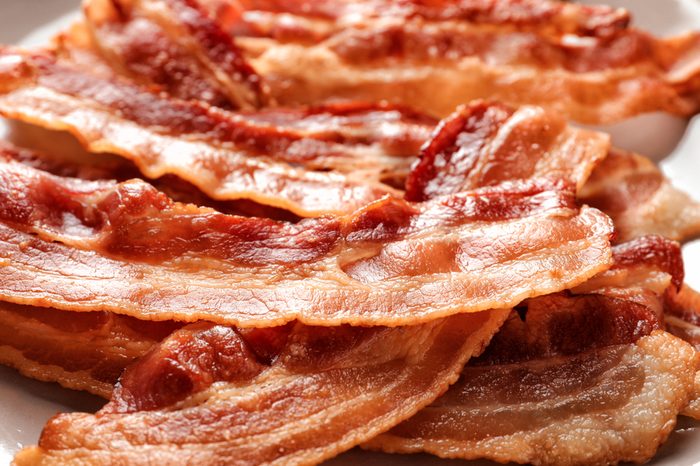 Cooked bacon rashers on plate, closeup