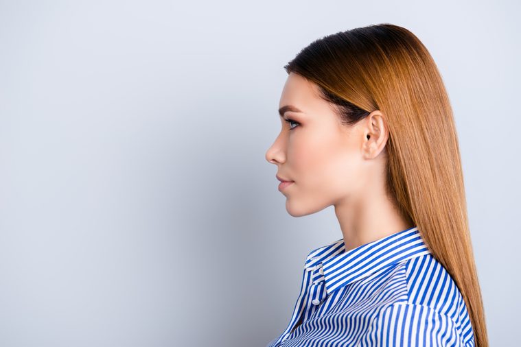 Close up cropped profile portrait of young business lady in striped shirt with serious face on pure background with copy space