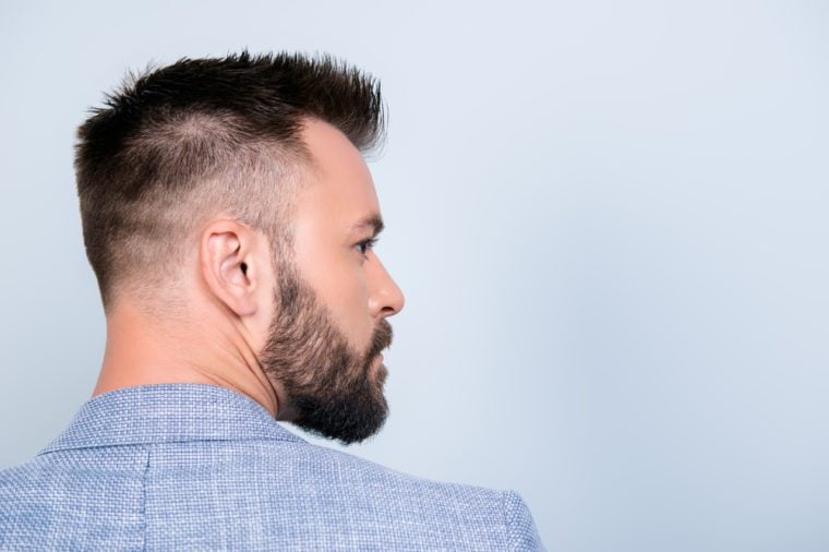 Back rear view of confident handsome brunet in smart casual, standing on the pure light blue background, with perfect hairstyle. So hot and attractive, harsh and fashionable
