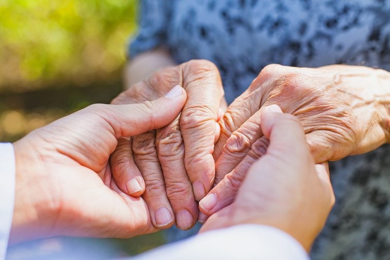 Close up medical doctor holding senior woman's shaking hands, Parkinson disease
