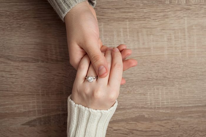 Top view of a male and female holding hands after a proposal of marriage. Female wearing an engagement ring