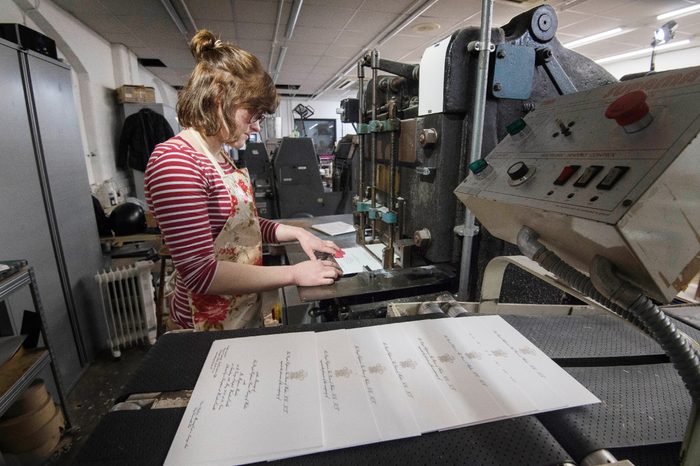 Lottie Small use the die stamping press at the workshop of Barnard and Westwood in London, who are printing the invitations for Prince Harry and Meghan Markle's wedding