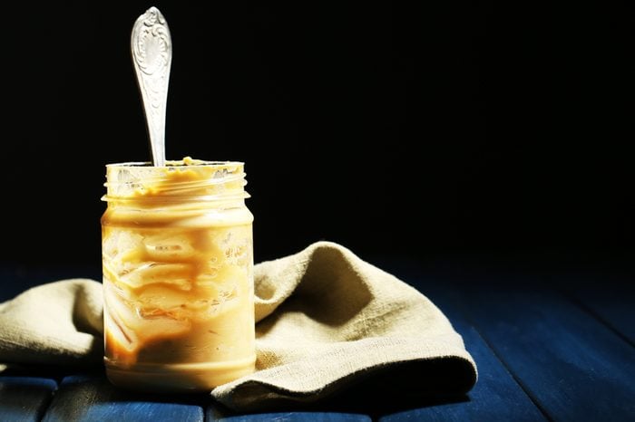 Empty peanut butter jar on table, on dark background