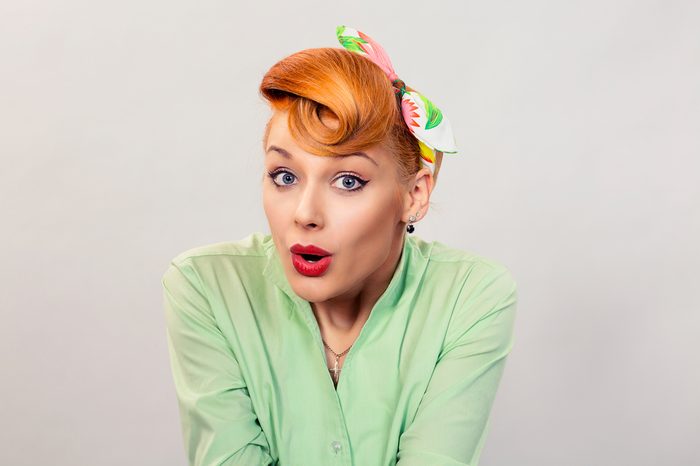 Wow. Closeup red head young woman pretty amazed pinup girl green button shirt excited surprised shocked looking at you camera retro vintage 50's hairstyle eyes mouth open. Human emotions body language