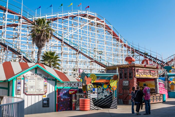 SAN DIEGO, CALIFORNIA - FEBRUARY 9, 2018: People walk on the midway at Belmont Park, an amusement park built in 1925 on the Mission Beach boardwalk with the iconic Giant Dipper roller coaster.