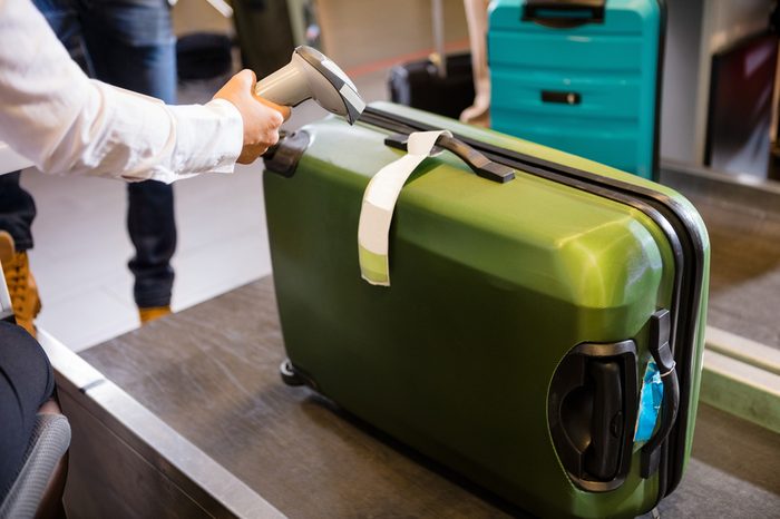 Woman Scanning Tag On Luggage At Airport Check-in
