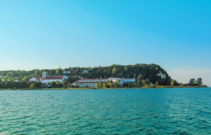 Mackinac Island in Northern Michigan, USA. Summer landscape with houses and trees on the shore, water and blue sky.