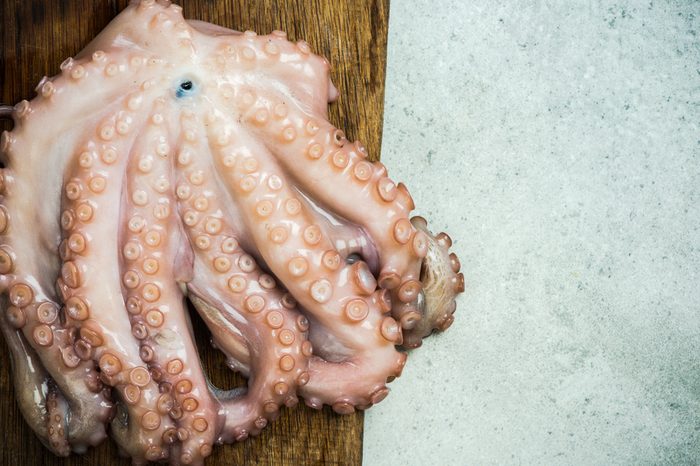 Whole fresh octopus on cutting board.