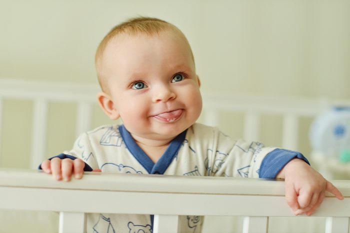 funny baby standing in the bed and showing tongue