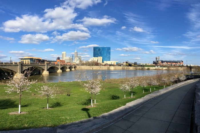 Downtown City Skyline Indianapolis Indiana White River in spring with blooming trees and vegetation, pedestrian bridges and ruins.