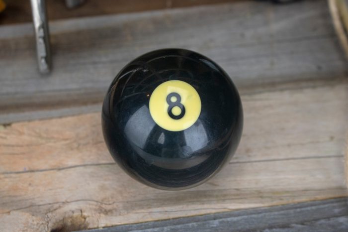 A magic eight ball sits on a distressed wood texture with lots of room for text! Vintage magic 8 ball! 