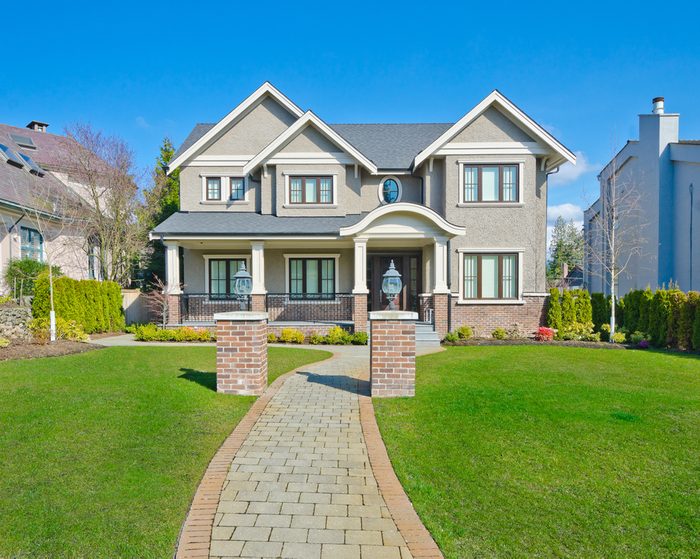 Big custom made luxury house with long doorway and nicely trimmed front yard in the suburbs of Vancouver, Canada.