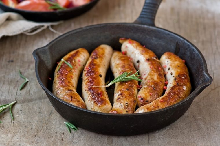 fried sausages on a frying pan on a wooden background