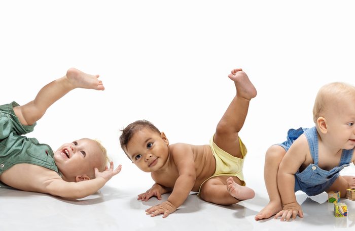 Multiethnic babies dancing on light background