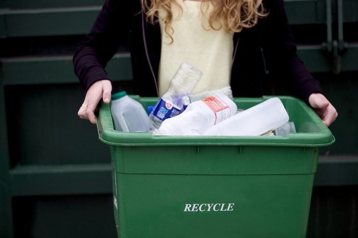 A teenage girl holding a recycling container