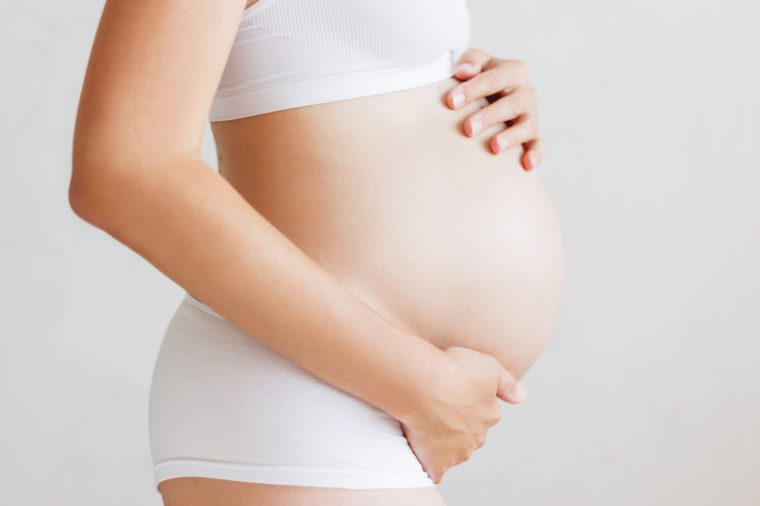 Pregnant woman in white underwear. Young woman expecting a baby. 
