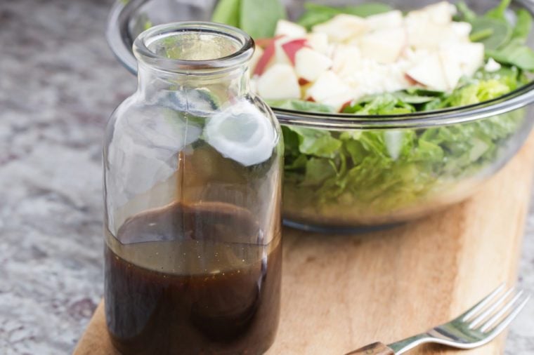 a glass bottle with salad dressing consisting of balsamic vinegar, honey and olive oil
