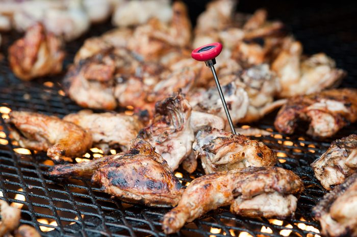 Barbecue chicken on grill with thermometer.