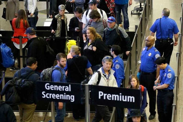 Travelers wait in line for security screening