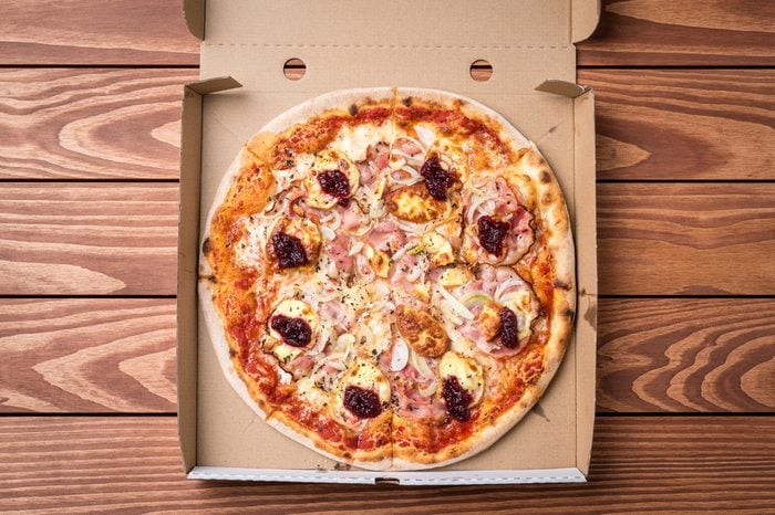 Pizza in cardboard box on wooden table