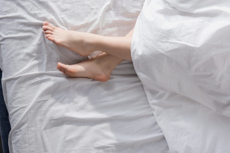 top view of beautiful female feet stretching out of blanket in morning