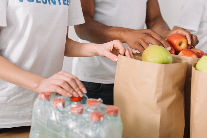 cropped shot of volunteers with apples and water bottles on table