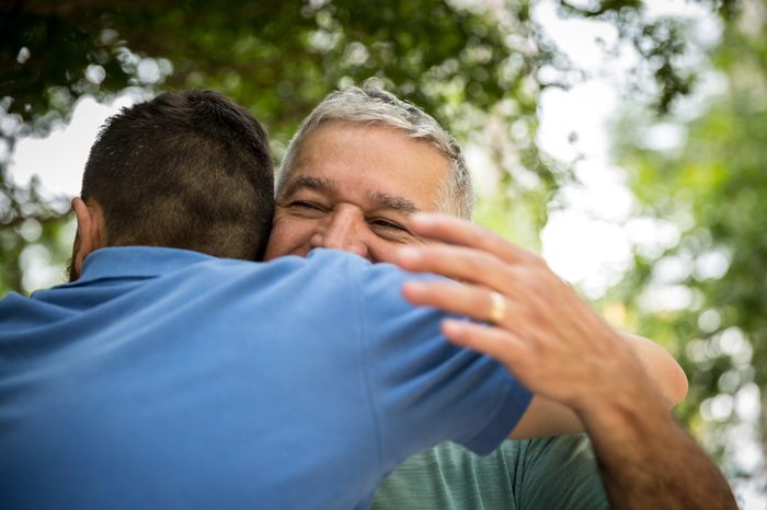 Adult son hugging his senior dad
