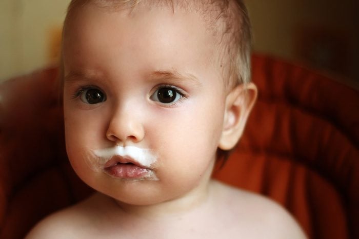 Cute baby boy with milk mustache, indoor portrait