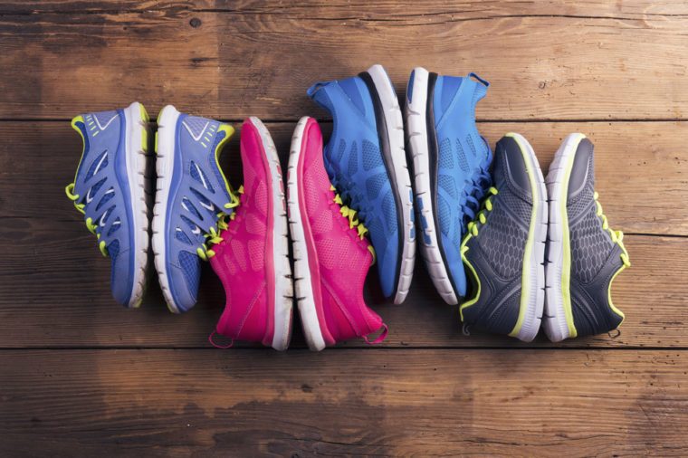 Four pairs of various running shoes laid on a wooden floor background