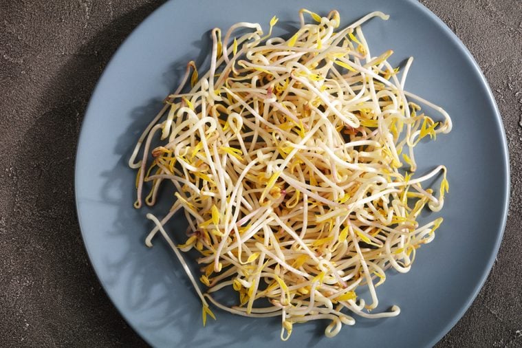 freshly grown mung Bean Sprouts on plate on concrete background, major ingredient of asian cuisine, view form above, close-up