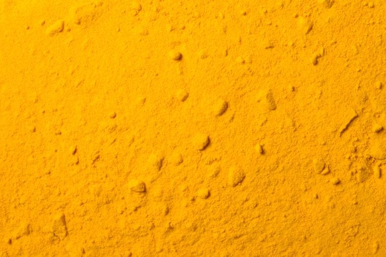 Close up photo on surface of ground turmeric pile, abstract yellow curcuma powder texture as background, overlay for art work