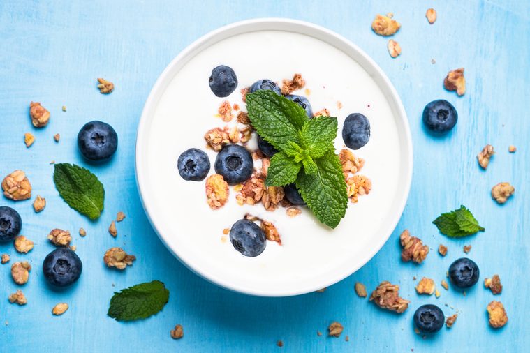 Greek yogurt granola and blueberries on blue table top view. Healthy food nutrition, snack or breakfast.