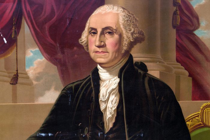 George Washington. Print showing George Washington, standing in front of a chair with right arm extended toward a table on the left and holding a sword in left hand.