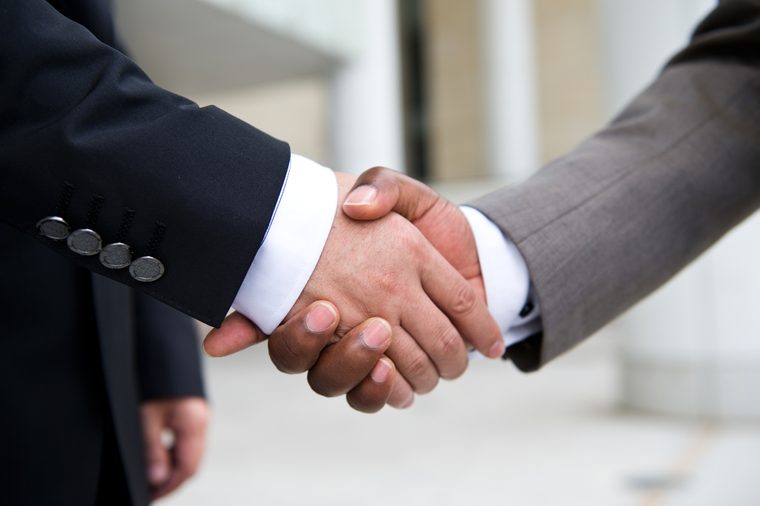 African businessman's hand shaking white businessman's hand making a business deal.