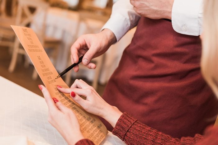 Cropped image of customer asking waiter about food in menu