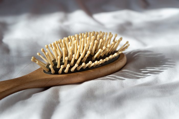 Hair fall, Hair loss problem. Wooden brown comb with hair loss on white bed cover. Woman healthy and beauty concept.