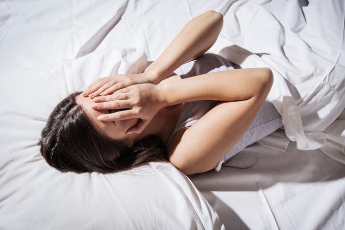 Depressed insomnia woman cover her face in bed.