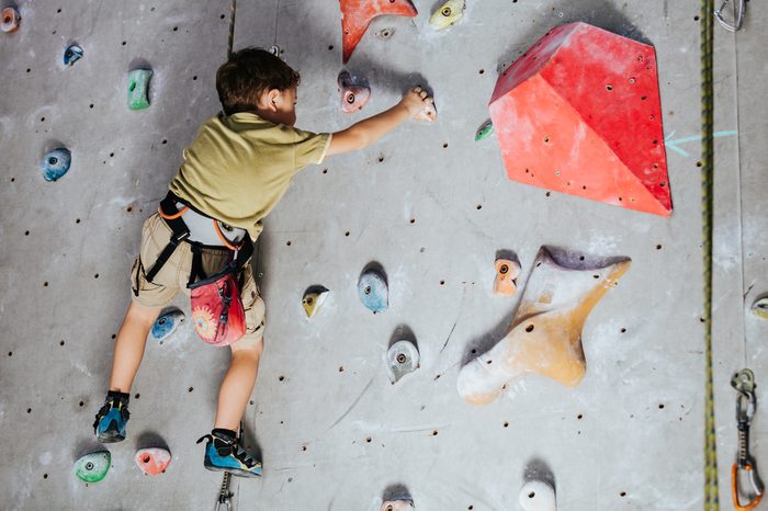 little boy climbing a rock wall indoor. Concept of sport life.