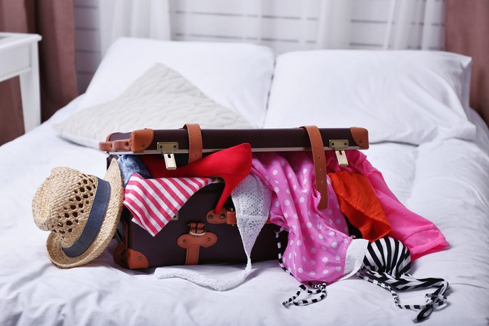 Suitcase with clothing on bed in room