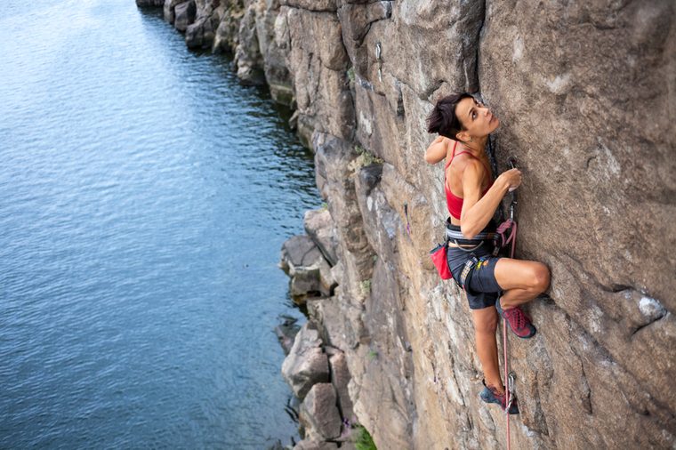 The girl climbs a climbing route over the water. extreme travel. Sport in nature.