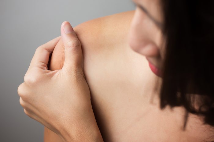 Woman pressing her hand against a painful shoulder