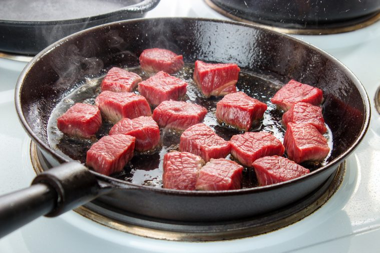 Searing beef bottom round roast cubes in cast iron skillet , meat just added to hot oil , the upper sides are still red