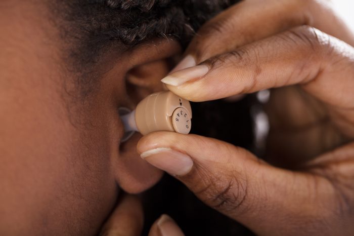 Close-up Of Doctor Inserting Hearing Aid In The Ear Of A Girl