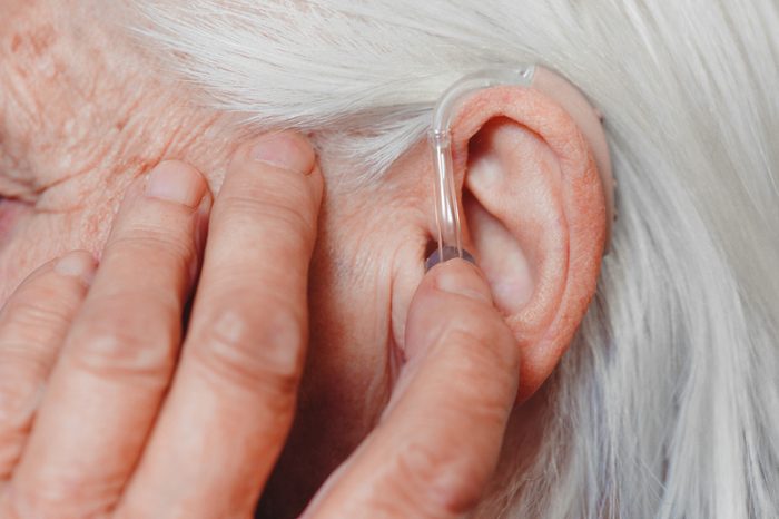 Closeup senior woman with hearing aid in her ear. Health care, hear amplify, device for the deaf.