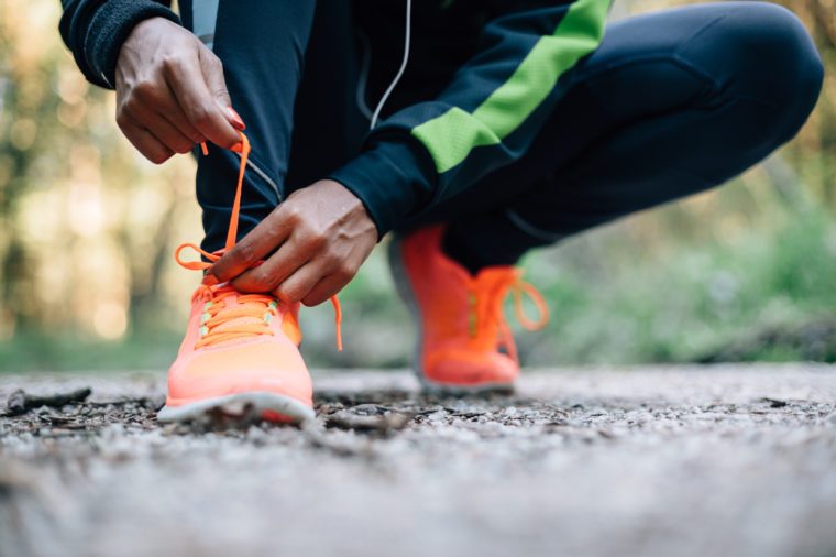 Young black woman runner tying sport shoes