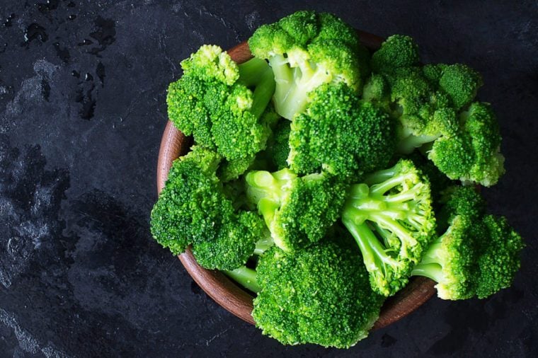 Fresh raw broccoli in a wooden bowl on a dark background