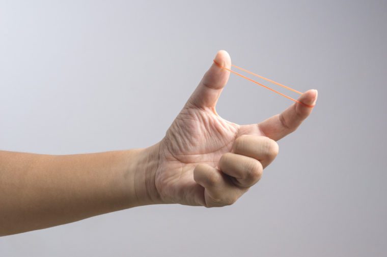 Hand holding elastic rubber band on white background